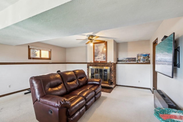 living room featuring ceiling fan, a brick fireplace, light carpet, and a textured ceiling