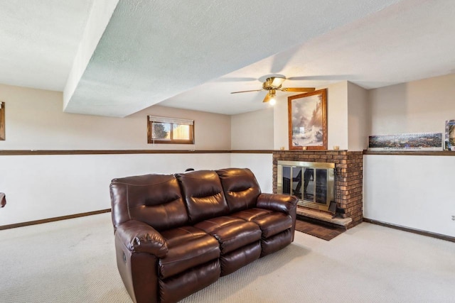 living room with a brick fireplace, light colored carpet, a textured ceiling, and ceiling fan