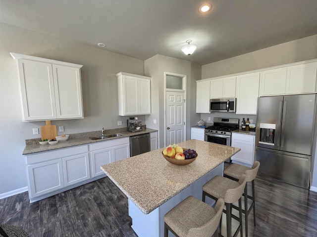 kitchen with dark wood-type flooring, sink, a center island, appliances with stainless steel finishes, and white cabinets