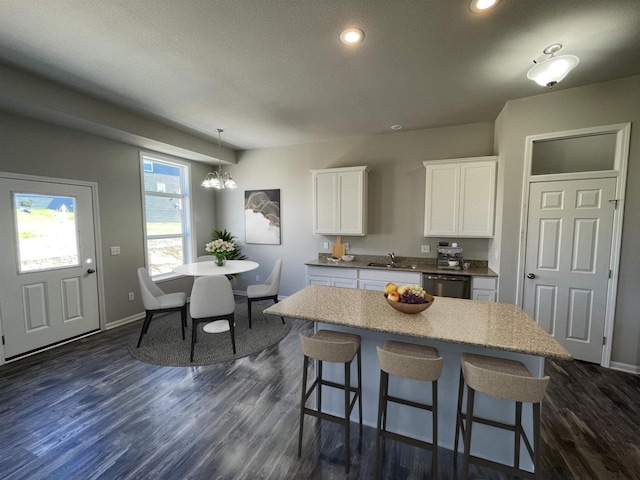 kitchen featuring sink, white cabinetry, stainless steel dishwasher, dark hardwood / wood-style floors, and a kitchen island