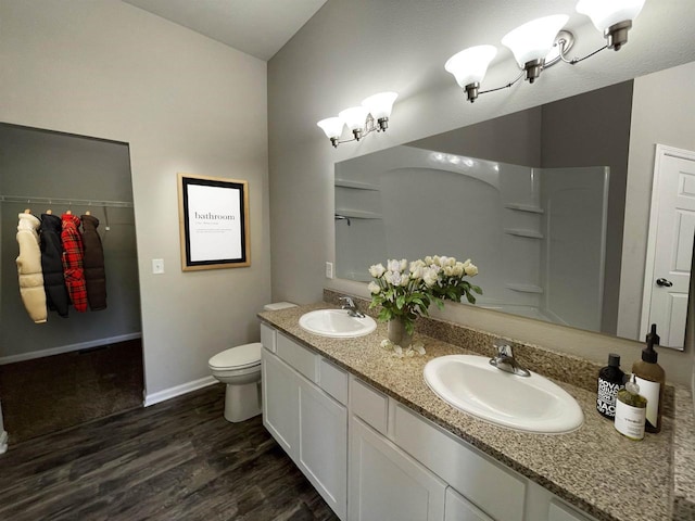 bathroom featuring vanity, wood-type flooring, a shower, vaulted ceiling, and toilet