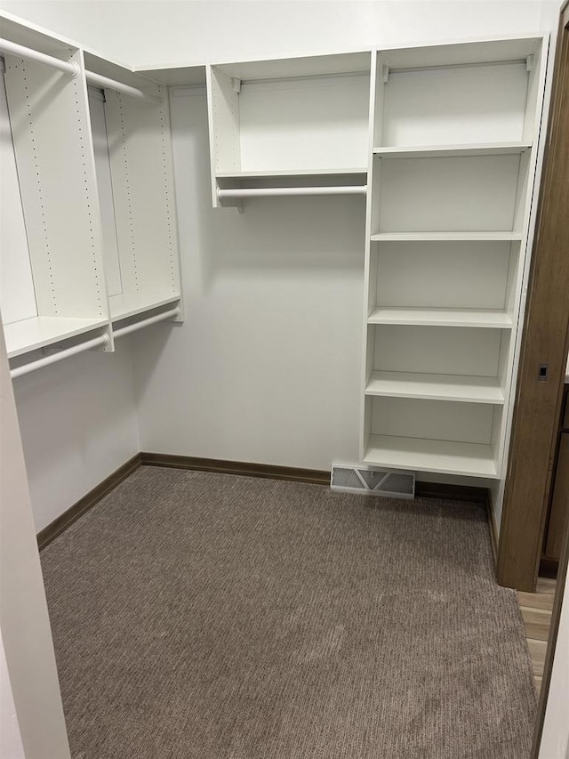 spacious closet with dark colored carpet