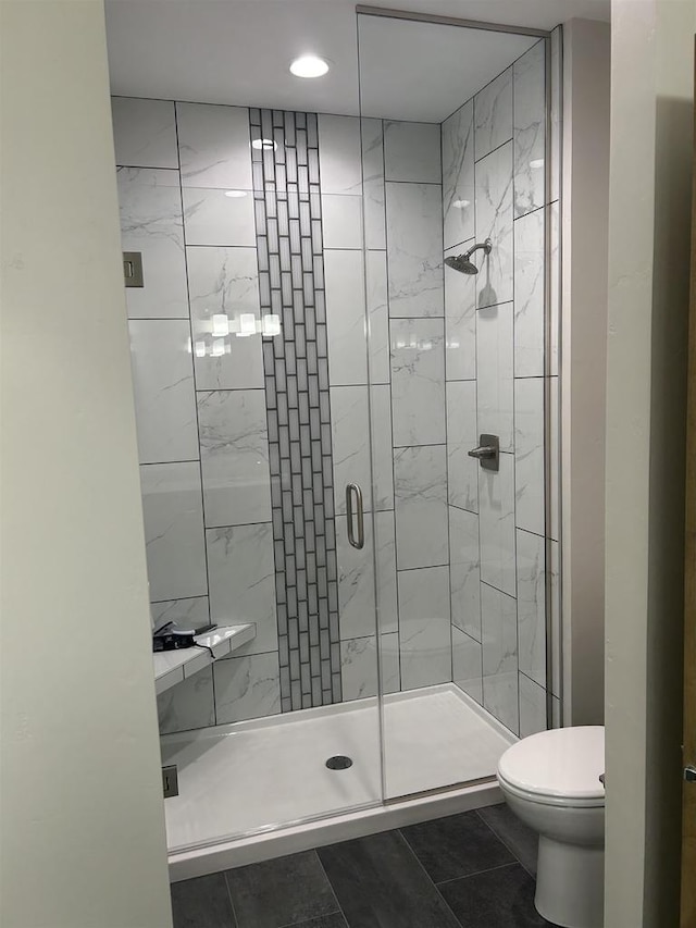 bathroom with toilet, tile patterned floors, and a shower with shower door