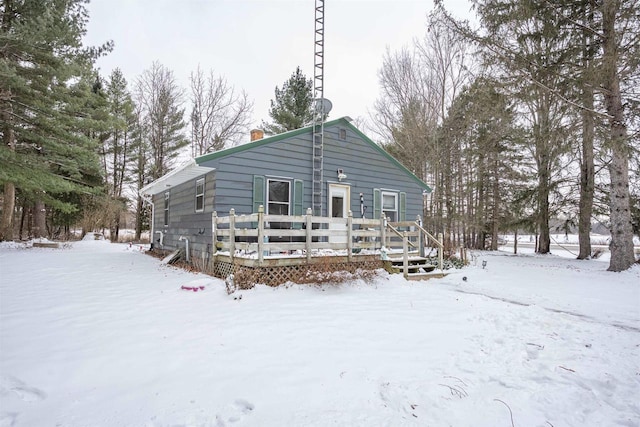 snow covered back of property featuring a deck