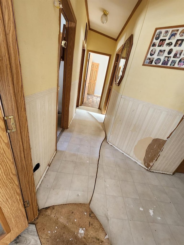 hallway with ornamental molding and light tile patterned flooring