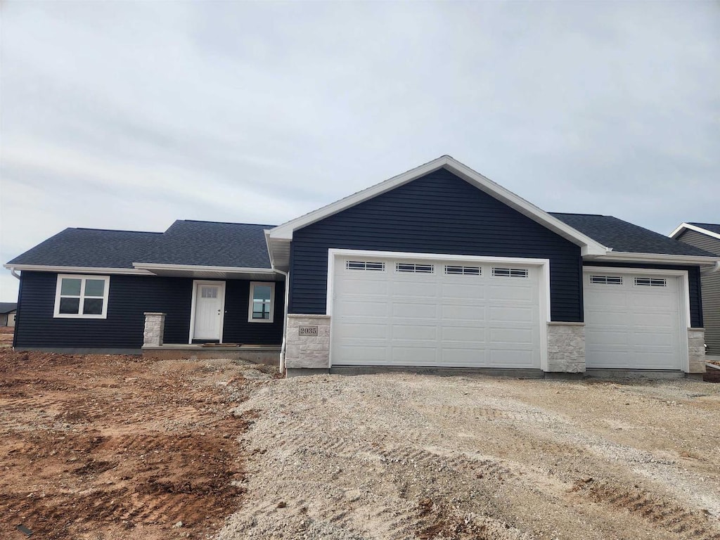 2035 Red Fox Ln, Kaukauna, WI 54130 - ranch-style home with driveway, a shingled roof, stone siding, and an attached garage