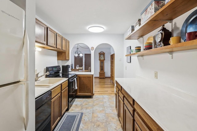 kitchen with a sink, black appliances, pendant lighting, and light countertops