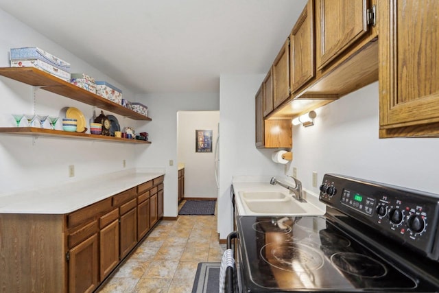 kitchen featuring light countertops, electric range, brown cabinetry, and a sink