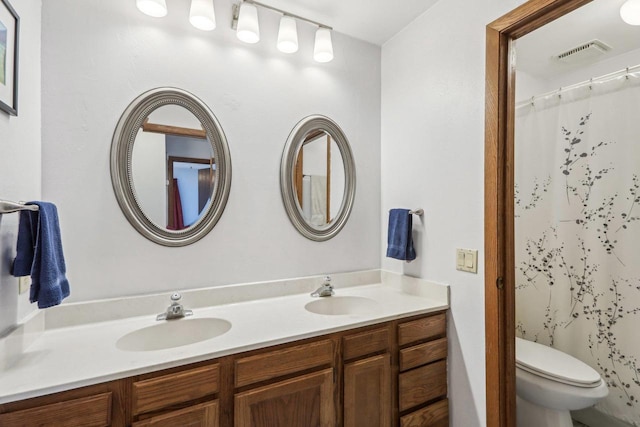 bathroom with visible vents, a sink, toilet, and double vanity