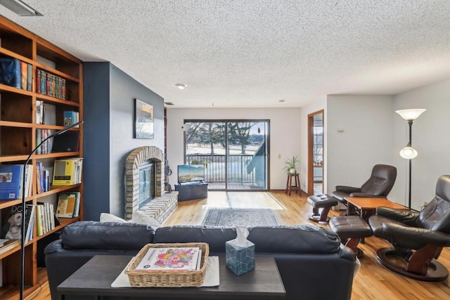 living area with visible vents, a textured ceiling, and wood finished floors