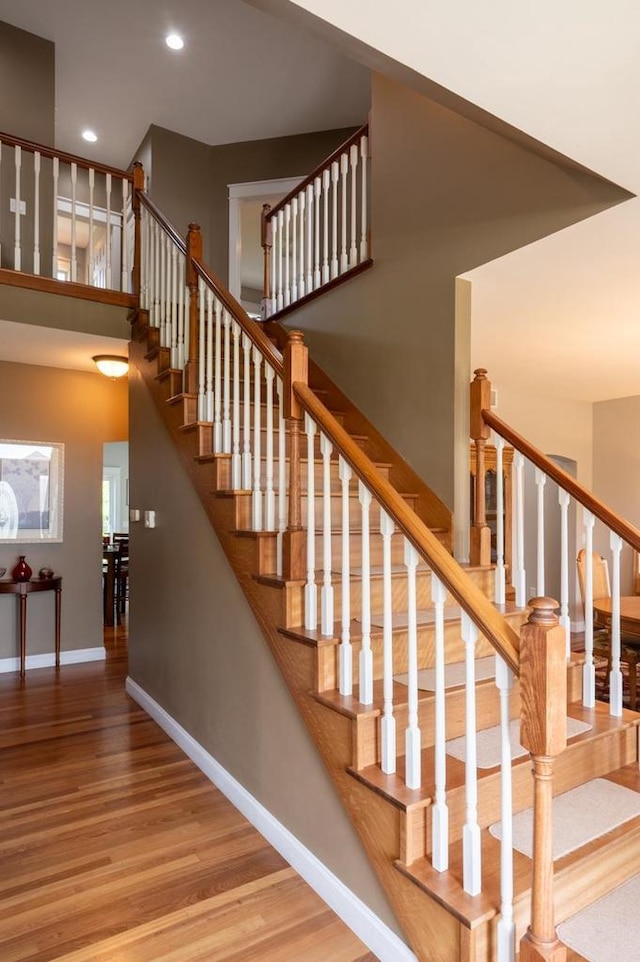 stairs featuring wood-type flooring and a high ceiling