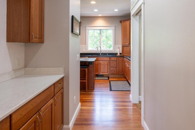 kitchen with wood-type flooring, light stone countertops, and sink