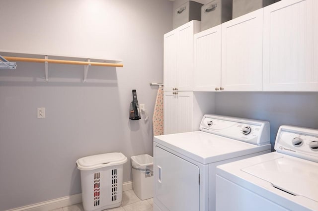 washroom featuring cabinets, light tile patterned flooring, and washer and clothes dryer