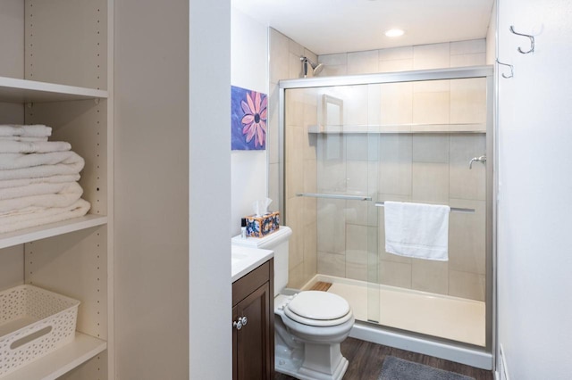 bathroom featuring vanity, hardwood / wood-style floors, a shower with shower door, and toilet