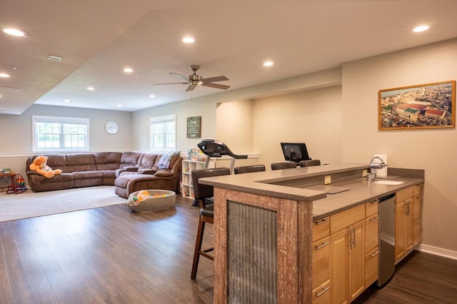 kitchen with sink, dark wood-type flooring, ceiling fan, a kitchen bar, and kitchen peninsula