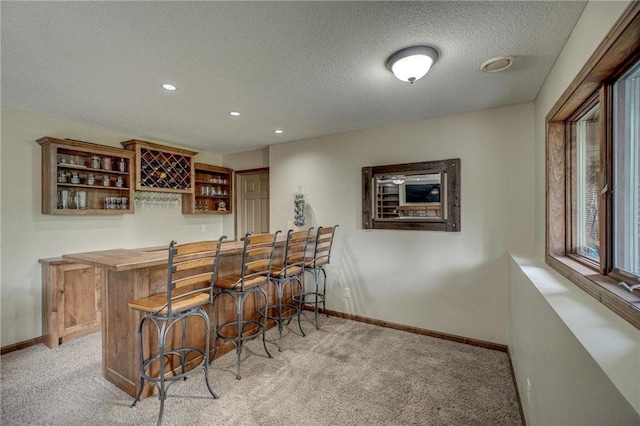 bar featuring light carpet and a textured ceiling