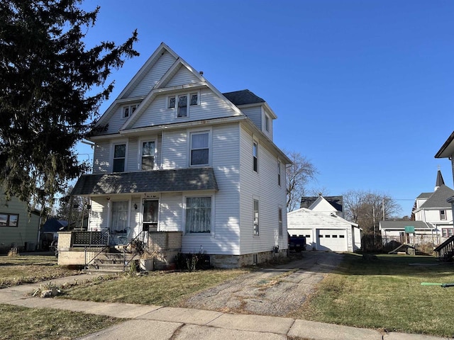 view of front of house featuring a garage, an outbuilding, a front yard, and a porch