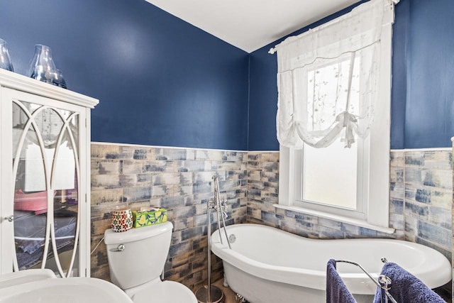 bathroom with a washtub, tile walls, and toilet