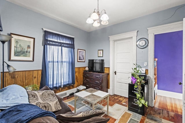 living room featuring hardwood / wood-style flooring, an inviting chandelier, and wooden walls