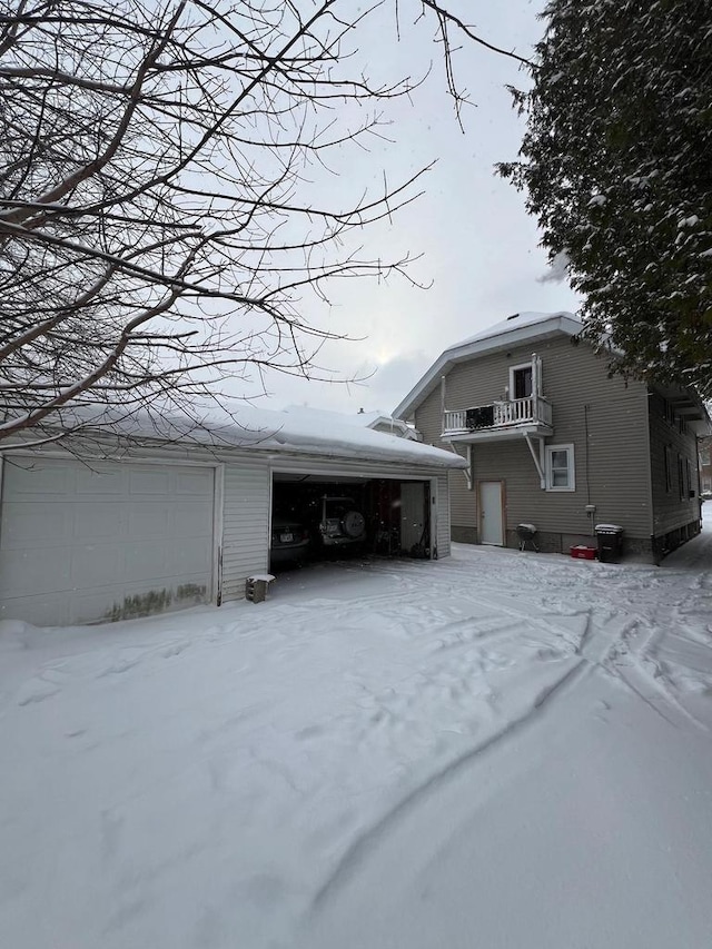 view of snow covered exterior with a balcony and a garage