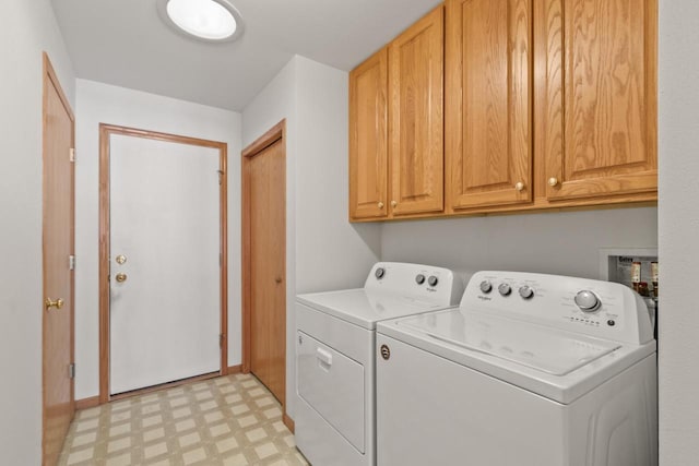 clothes washing area with separate washer and dryer and cabinets