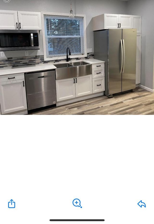 kitchen with white cabinetry, stainless steel appliances, sink, and light hardwood / wood-style flooring