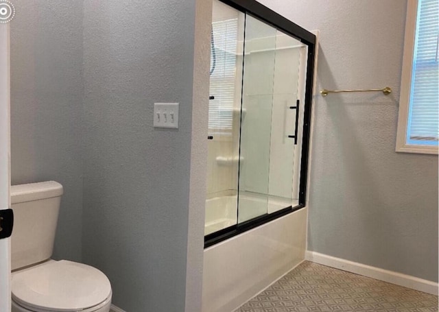 bathroom featuring combined bath / shower with glass door and toilet