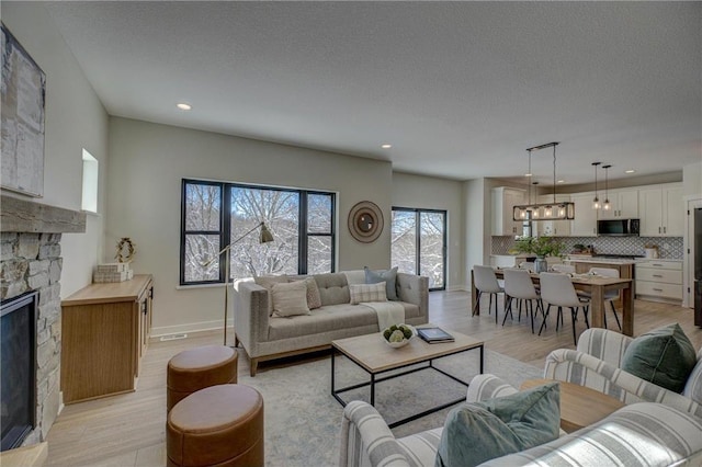 living room featuring a fireplace, light hardwood / wood-style flooring, and a textured ceiling