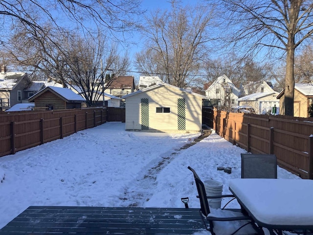 yard covered in snow with a fenced backyard, a residential view, outdoor dining area, and an outdoor structure