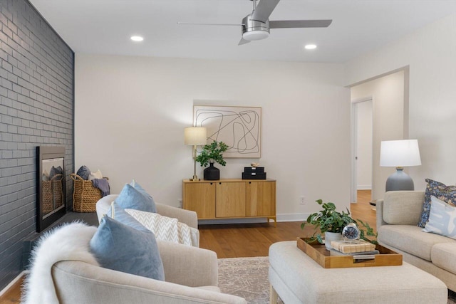 living room featuring a brick fireplace, light hardwood / wood-style flooring, and ceiling fan