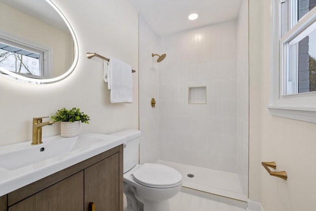 bathroom featuring vanity, toilet, and a tile shower