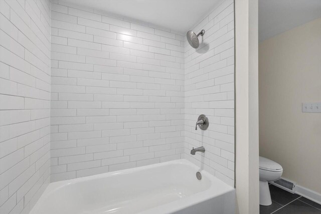 bathroom with tiled shower / bath combo, tile patterned floors, and toilet