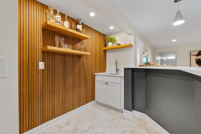 bar with white cabinetry, sink, and hanging light fixtures