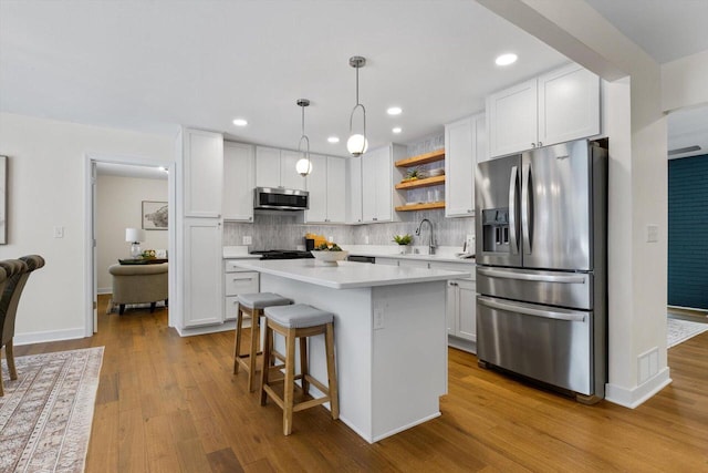 kitchen with stainless steel appliances, a kitchen island, white cabinets, and decorative light fixtures