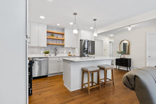 kitchen with sink, decorative light fixtures, a center island, appliances with stainless steel finishes, and white cabinets