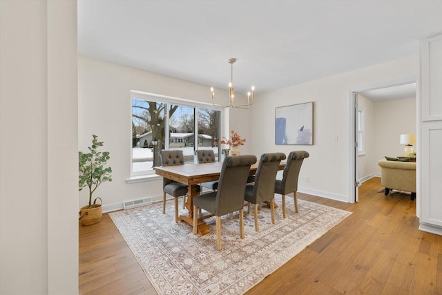 dining space featuring an inviting chandelier and light hardwood / wood-style flooring