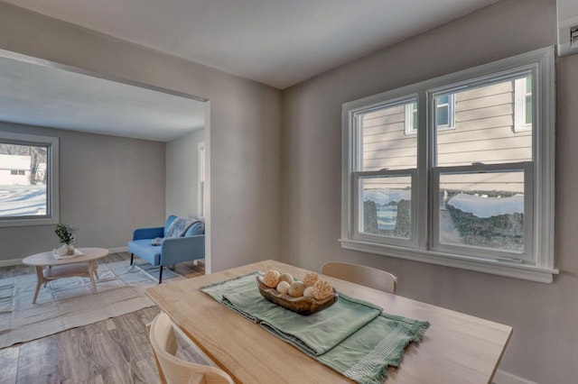 dining space featuring light wood-style flooring and baseboards