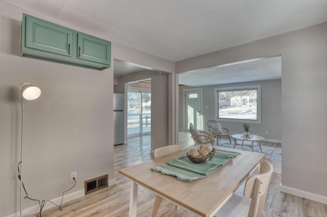 dining space with light wood-style floors, plenty of natural light, and visible vents