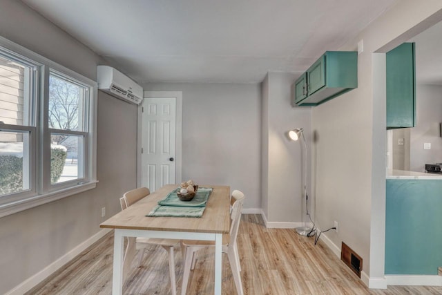 dining space with baseboards, light wood-style flooring, visible vents, and an AC wall unit