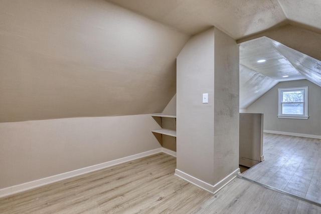 bonus room with lofted ceiling, light wood-type flooring, and baseboards