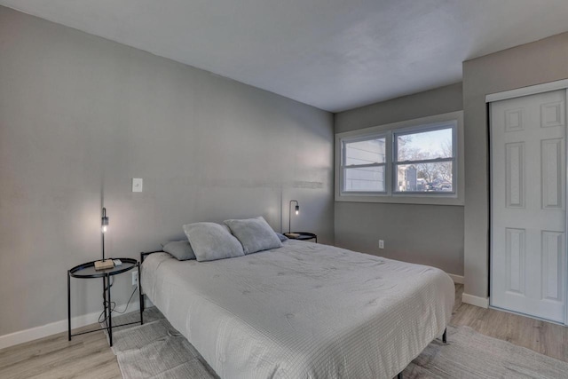 bedroom with light wood finished floors, baseboards, and a closet