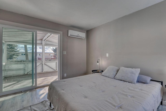 bedroom featuring access to exterior, wood finished floors, and a wall mounted air conditioner