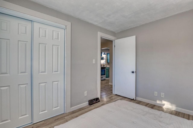 bedroom with light wood finished floors, a closet, and baseboards