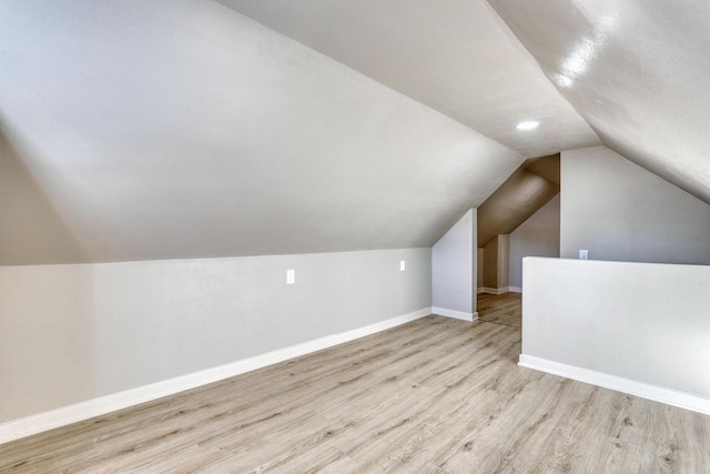 additional living space featuring lofted ceiling, light wood-style flooring, and baseboards