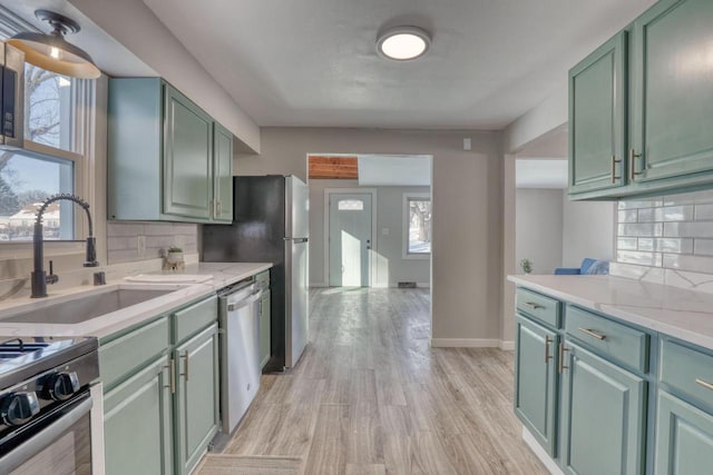 kitchen featuring appliances with stainless steel finishes, green cabinetry, a sink, and tasteful backsplash