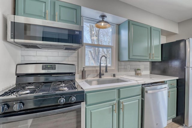 kitchen featuring decorative backsplash, appliances with stainless steel finishes, green cabinets, and a sink