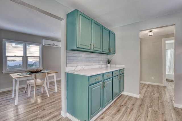 kitchen featuring light wood-style flooring, baseboards, light countertops, an AC wall unit, and decorative backsplash