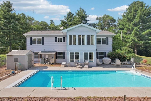 back of house featuring a fenced in pool, a patio area, and a storage unit