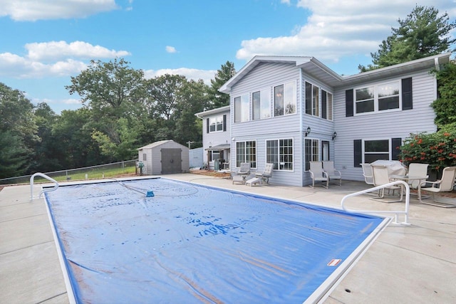 view of swimming pool featuring a shed and a patio area