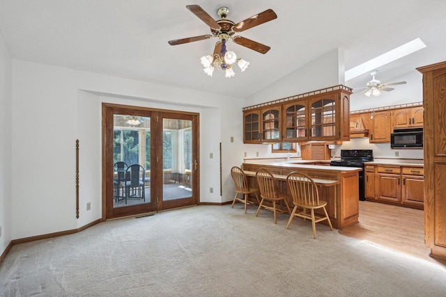 kitchen featuring light colored carpet, a breakfast bar area, black appliances, and kitchen peninsula